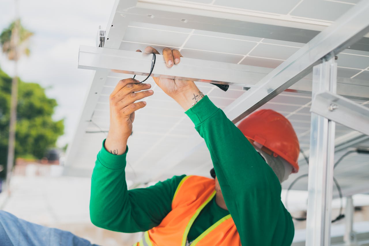 A solar technician in PPE installs a solar panel, showcasing renewable energy work.