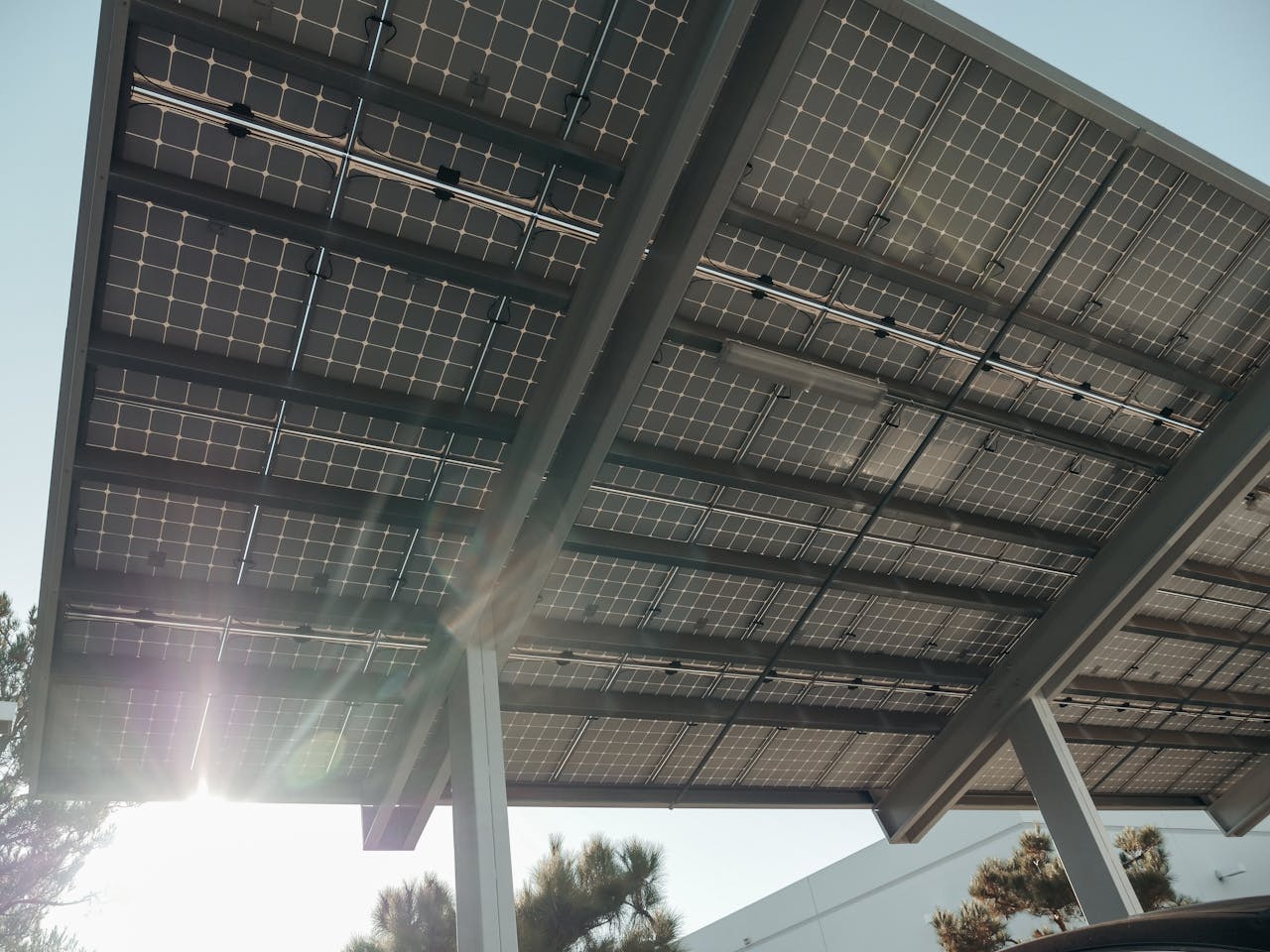 Close-up of solar panels on metal structure with sunlight filtering through, emphasizing sustainable energy.